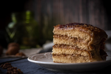Homemade cake with walnuts on a white plate. Wooden background.