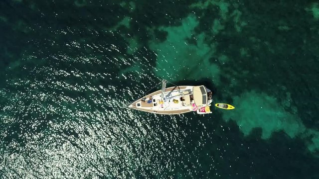Aerial view above sailboat swinging on agitated waters in the coast of Greece.
