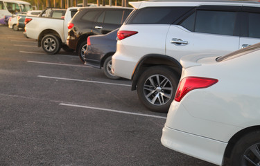 Closeup of rear side of white car parking in parking lot in the evening. 