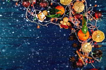 Obraz na płótnie Canvas Beautiful New Year decor on a black wooden background. Christmas layout with free space for your text. Gingerbread, lanterns, mandarins and other attributes of winter.