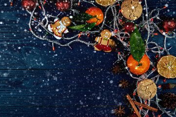 Obraz na płótnie Canvas Beautiful New Year decor on a black wooden background. Christmas layout with free space for your text. Gingerbread, lanterns, mandarins and other attributes of winter.