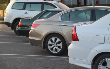 Closeup of rear side of white car parking in parking lot with sunlight in the evening. 