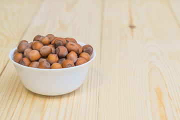 hazelnut nuts in white plate on wooden background