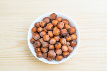 hazelnut nuts in white plate on wooden background