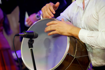 Men's hands play national music on the drum.