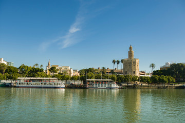 Fototapeta na wymiar Golden Tower in Seville with the Guadalquivir river and a beautiful blue sky at sunset (Torre del Oro, Sevilla) Andalusia, Spain