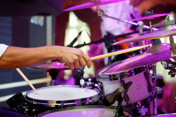 Male hands play with drumsticks on the drum set.