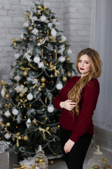 Happy young lady with long hair gifts by the fireplace near the Christmas tree