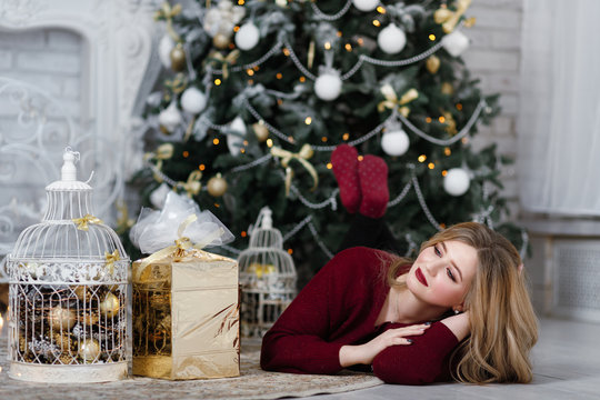 Happy young lady with long hair gifts by the fireplace near the Christmas tree