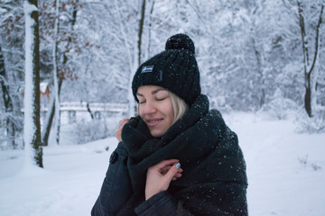 Pretty girl enjoying snowy weather in a winter park.