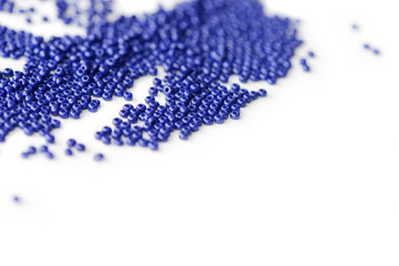 Dark blue seed beads scattered scattered on a white surface close up