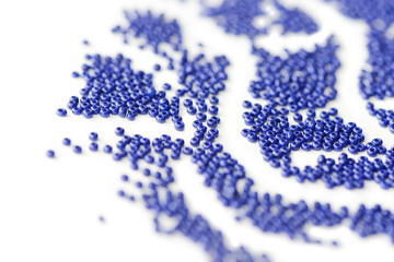 Dark blue seed beads scattered scattered on a white surface close up