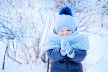little boy in a blue hat and blue scarf on a walk in the winter in the park, with