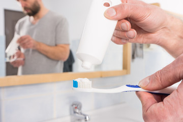 Person putting toothpaste on toothbrush