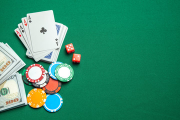 Concept of gambling in casino, sports poker. Playing cards with dice and colored chips with cash money dollars on green gaming table. Copy space for text.