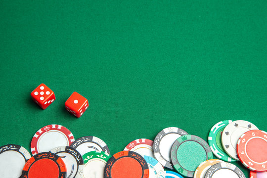 Concept of gambling in casino, sports poker. Gaming dice and colored gaming chips on green gaming table. Copy space for text.