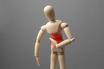 Pain in the abdomen, stomach. The wooden man holds his hands on the belly of the red