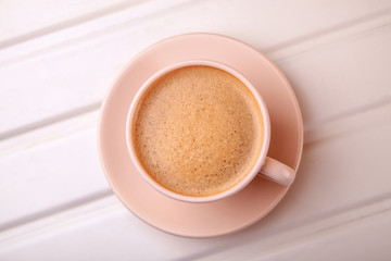 Cup of coffee with foam on white table. Top view