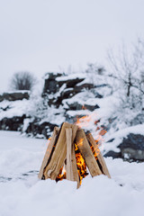 Camp fire in winter time, surrounded by snow against the background of the frozen lake. Concept adventure active vacations outdoor hiking sport 