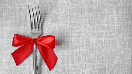 A fork with a red bow lies on the tablecloth. A place to record. Photo for the menu of cafe, restaurant, dining room, pizzeria. A place for a festive menu.