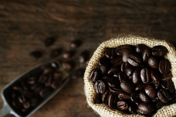 Coffee beans is a sack on wooden table.