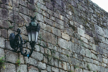 Medieval street lamp on old brick wall colored. Facade of ancient buiding, Europe. Grunge outdoor design. Old castle wall. Stone wall textured. Architecture and travel concept. Vintage wallpaper.