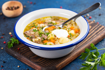  Rassolnik - Traditional Russian soup with pickled cucmbers, pearl barley, meat, pickles, carrots and potatoes  on blue background. Top view