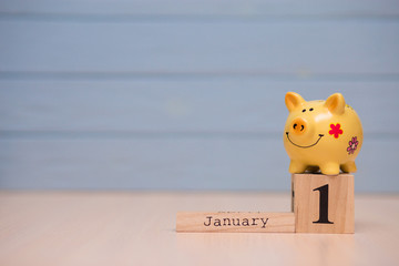 Calendar date of Financial Year start, 1st january with piggy bank on blue background. Winter time.