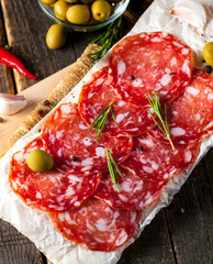 Chorizo sausage and salami, thin cut. spanish salami on the wood background with spices, paprika, pepper. Spicy food. Chili.