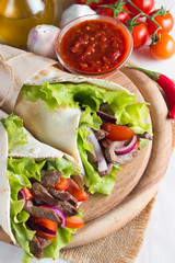Photo of Mexican sandwich food, burrito, fajita, tacos, wrap made of tortilla, beef, chicken, fresh vegetables on rustic wooden background. Fast food concept. Healthy lunch snack. Copy space. 