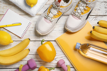 Flat lay composition with sport items, healthy food and notebooks on wooden background. Weight loss...