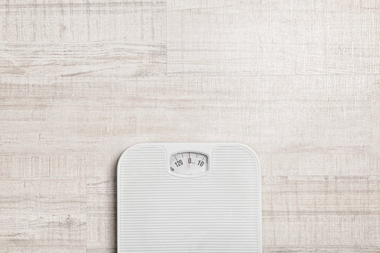 Bathroom scales and space for text on wooden background, top view. Weight loss concept