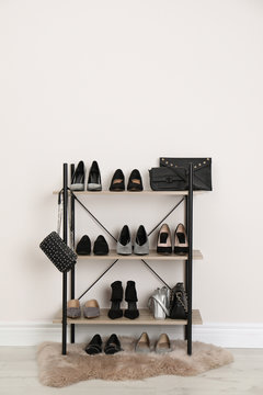 Shelving unit with stylish shoes and purses near white wall. Element of dressing room interior