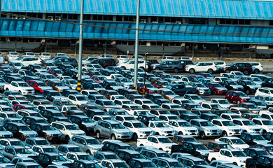 New car parked in a row at parking lot of factory. Car dealer inventory stock. Automotive industry. Car dealership concept. Concrete parking area for stock car after production line at manufacturing.