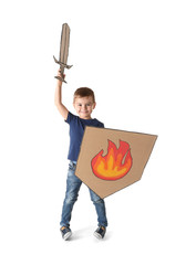 Cute little boy playing with cardboard sword and shield on white background
