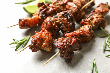 Delicious barbecued meat with rosemary on grey background, closeup