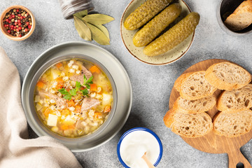 Rassolnik - Traditional Russian soup with pickled cucmbers, pearl barley, meat, pickles, carrots and potatoes  on light background. Top view