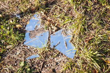 Large broken glass plate abandoned in the fields in the middle of the nature