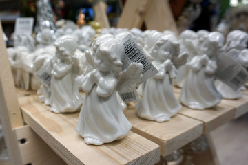 Decorative porcelain figures of little angels at Christmas market. Traditional market with handmade souvenirs