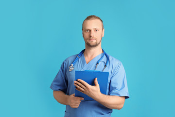 Portrait of medical assistant with stethoscope and clipboard on color background