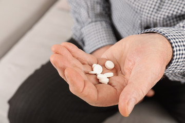 Senior man holding pills in hand, closeup