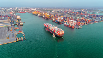 Aerial view Tug boats drag container ship to sea port and working crane bridge loading container for import  export or transportation concept background.
