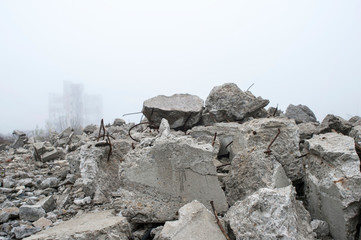 The remains of concrete fragments of gray stones on the background of the destroyed building in a...