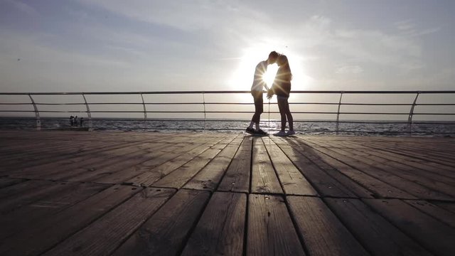 Silhouette of a couple in love. Romantic couple kissing on the beach. Contraception, first love, protection