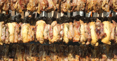 big skewers of chicken and pork meat while they cook very slowly