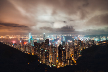 Beautiful Hong Kong island cityscape, aerial night view from Victoria Peak in cloudy storm weather. Asia tourism, business financial district, tourist attraction, or Asian travel destination concept