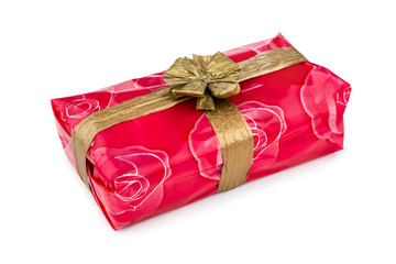 Gift box wrapped in red rose cellophane, decorated with golden raffia ribbon and bow isolated on the white background