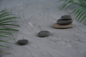 Pyramids of gray zen pebble meditation stones with green leaves on the gray background. Concept of harmony, balance and meditation, spa, massage, relax