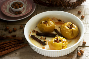 Baked apples with raisins, hazelnuts and cinnamon on wooden background. Rustic style.