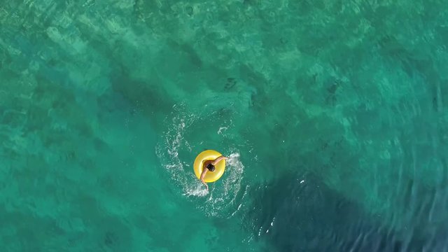 Aerial view of woman spinning with inflatable on Atokos island, Greece.